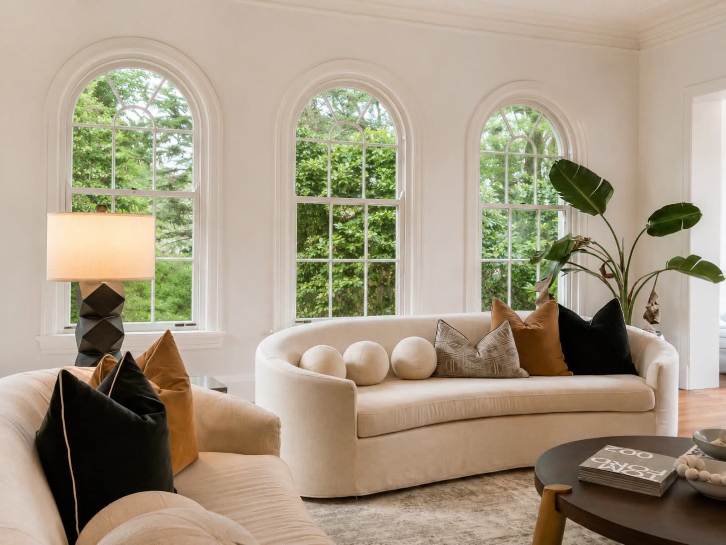 Living room with arched windows, a curved cream sofa and a black lamp