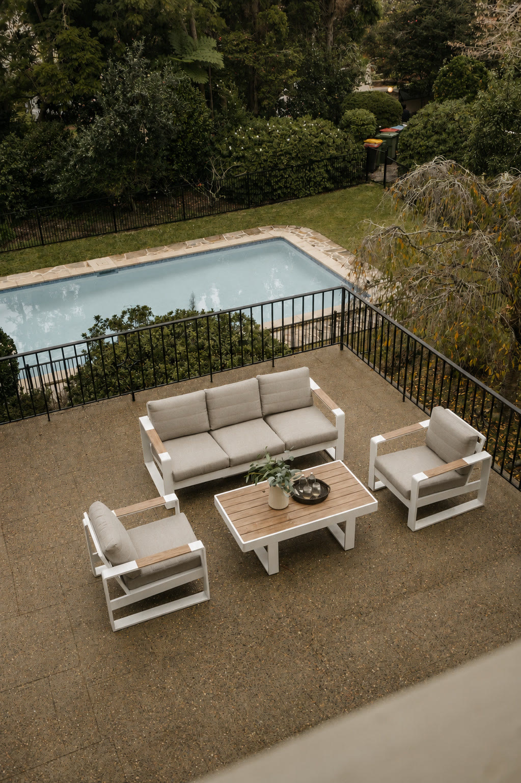 Garden pool seen from above, with a cream outdoor lounge setting on the paved terrace