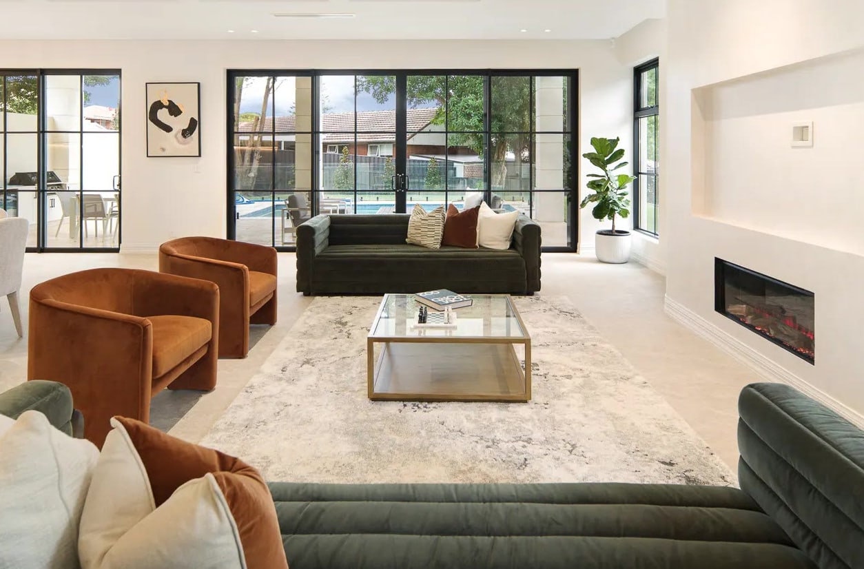 Rust velvet armchairs and a glass-topped coffee table in front of deep green channelled sofas