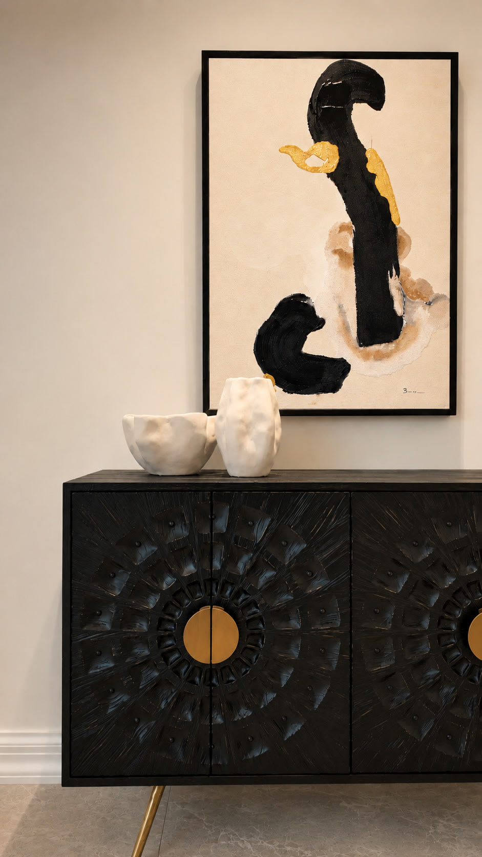Black carved sideboard with a brass disc handle beneath an abstract painting