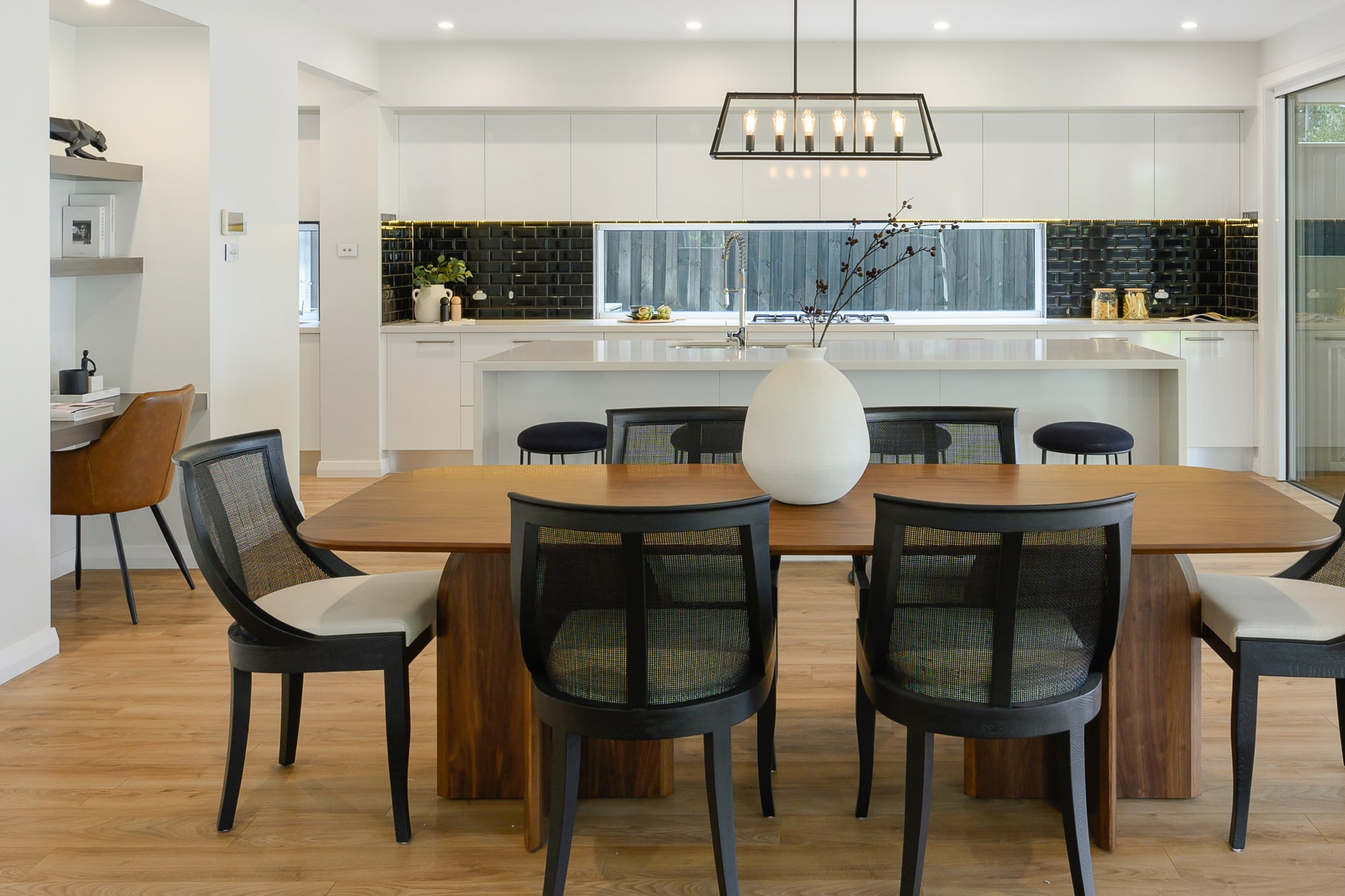 Timber dining table with black woven dining chairs and a centrepiece