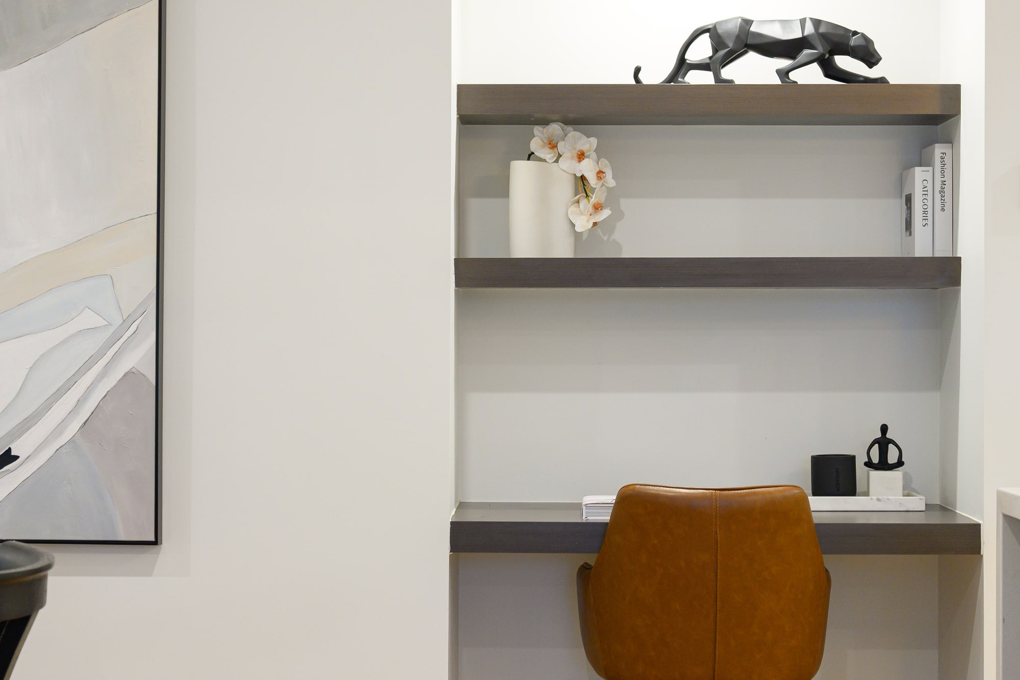 Built-in study nook with an orange chair, styled shelves and a black sculpture