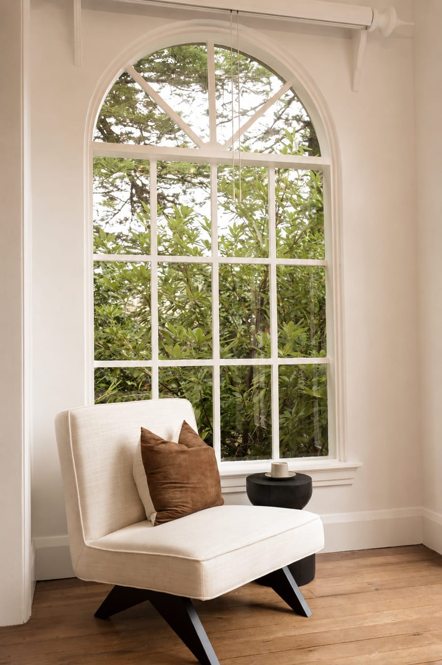 Cream lounge chair beside an arched window