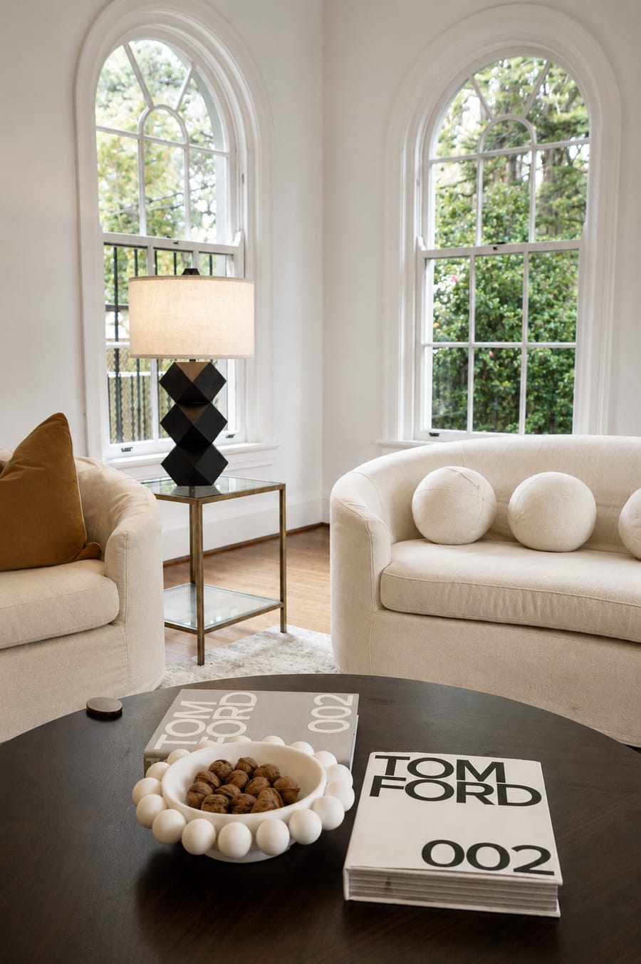 Armchairs and a round coffee table by tall sash windows