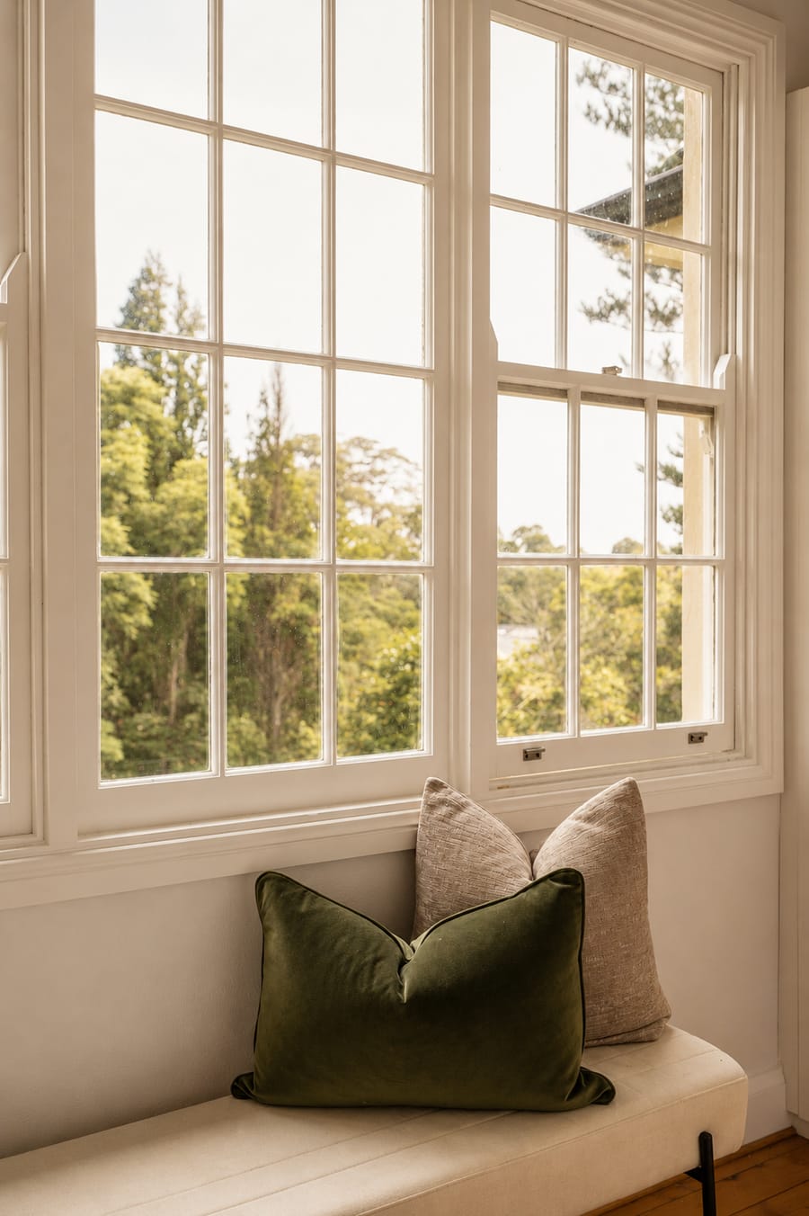 Window seat with a green velvet cushion and garden views